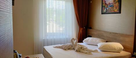 Una habitación de hotel con una cama bien hecha, un cuadro en la pared y una ventana con cortinas.