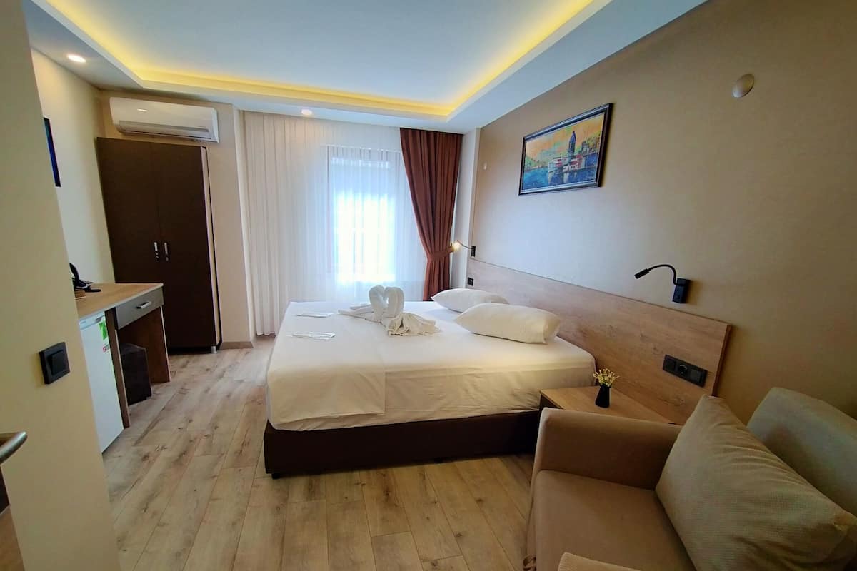 Een hotelkamer met een bed, een bureau, een stoel en een schilderij aan de muur.