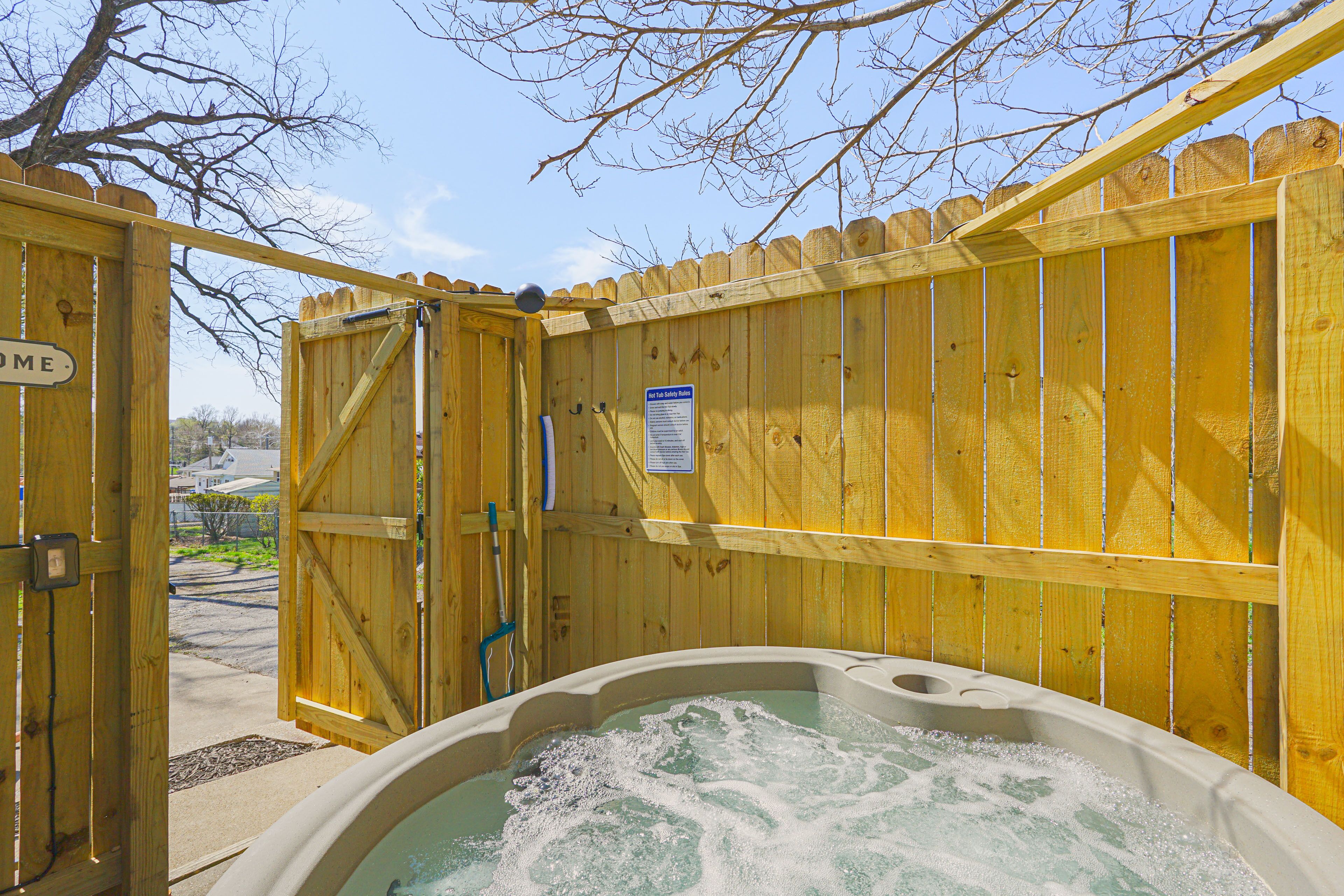 A wooden gate with a sign that reads "Welcome," leading to a hot tub area.