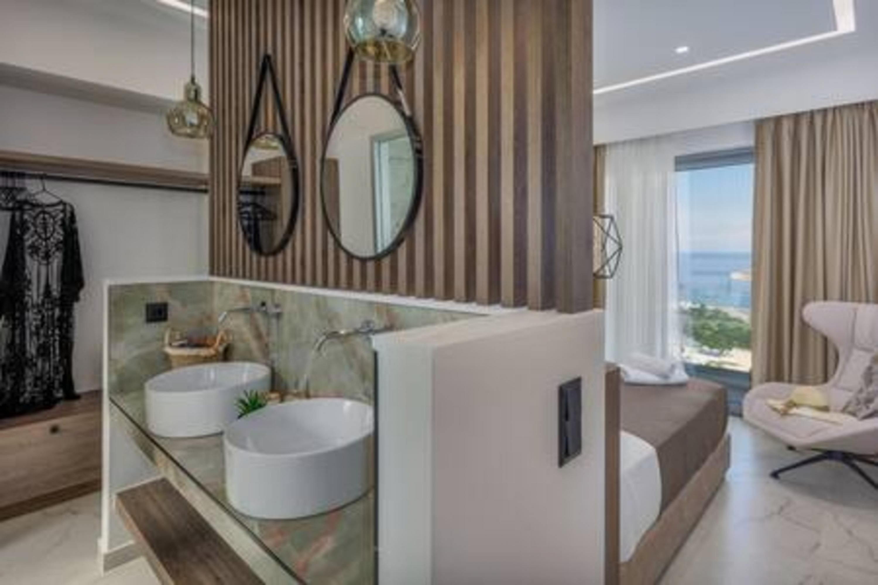 Un baño moderno con dos lavamanos redondos, un espejo grande y vistas al océano.