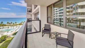 Un balcon avec vue sur l’océan, une piscine et un ensemble d’immeubles.