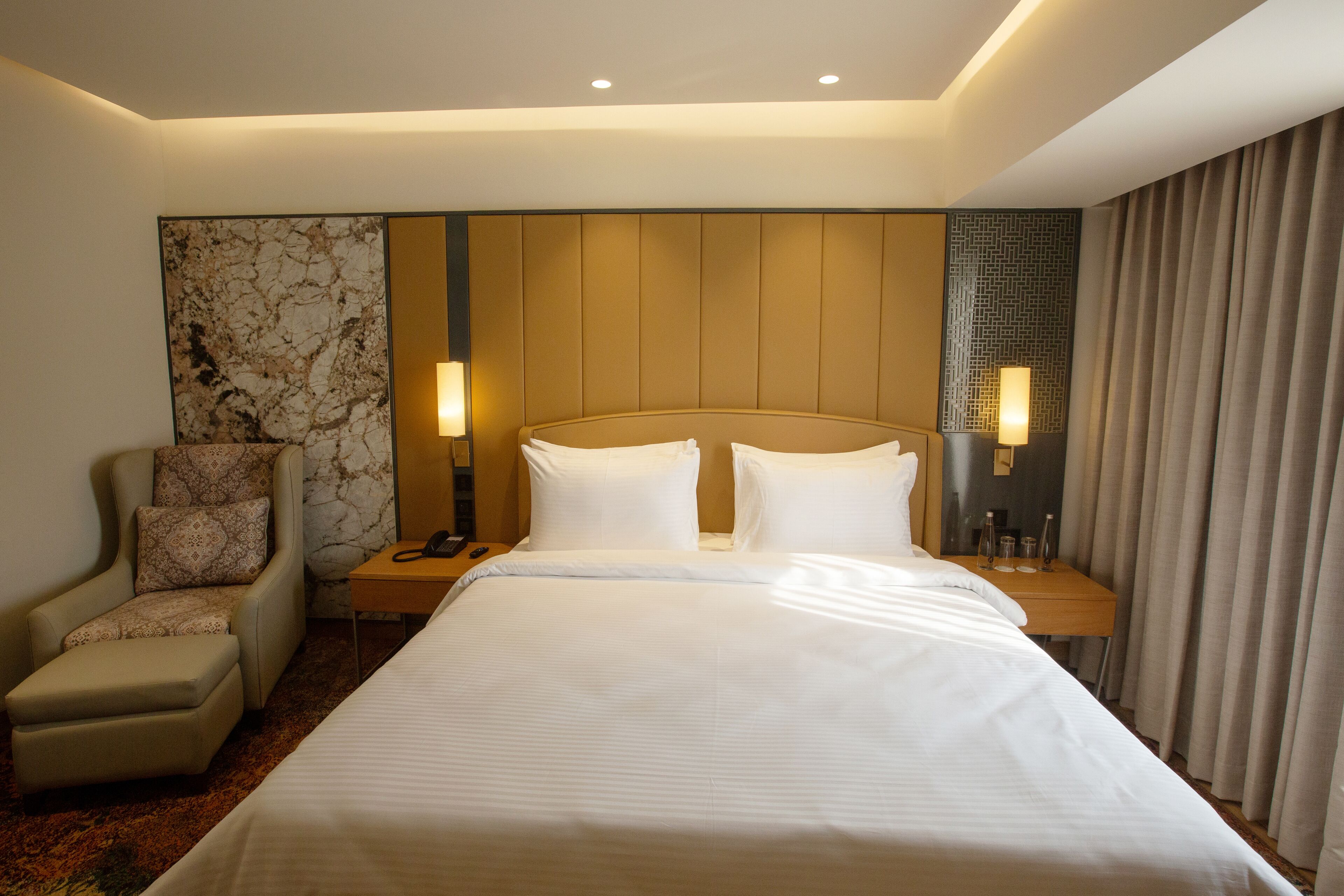 Ein Hotelzimmer mit einem großen Bett, einem Sessel, einem Nachttisch und einer Lampe.