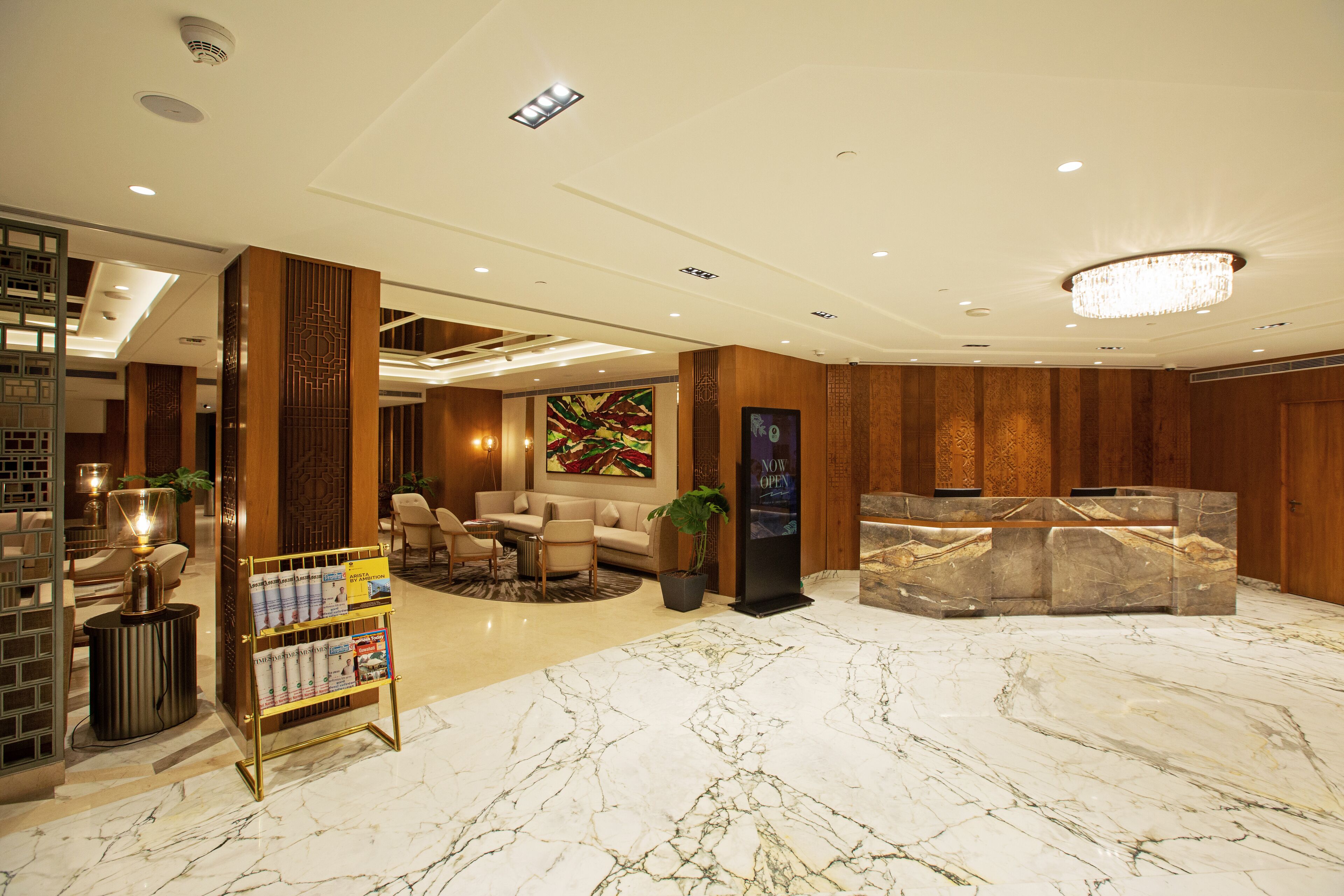 Un vestíbulo de hotel con recepción, zona de estar y suelo de mármol.