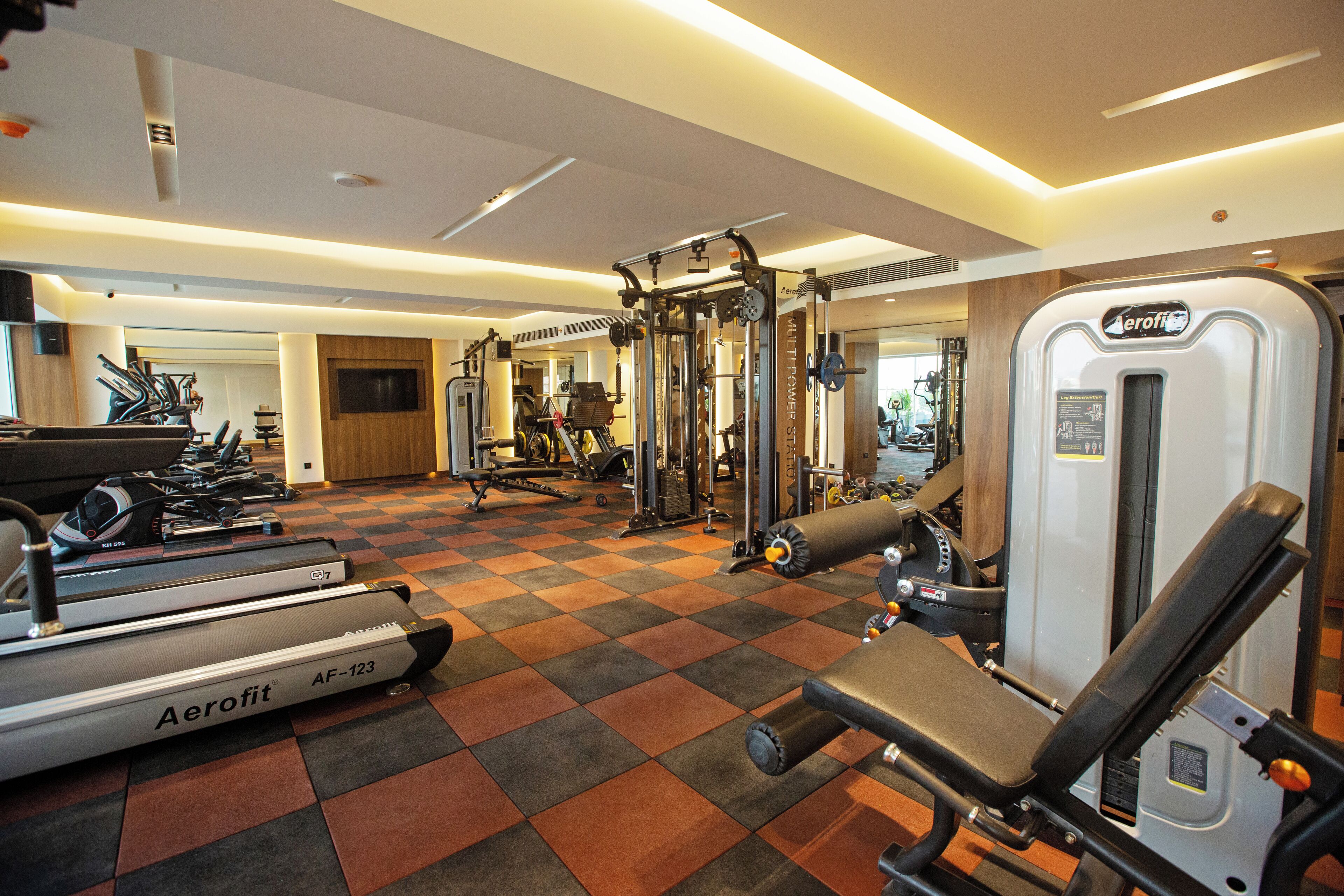 Un gimnasio con varios equipos de ejercicio, incluyendo cintas de correr y máquinas de pesas.