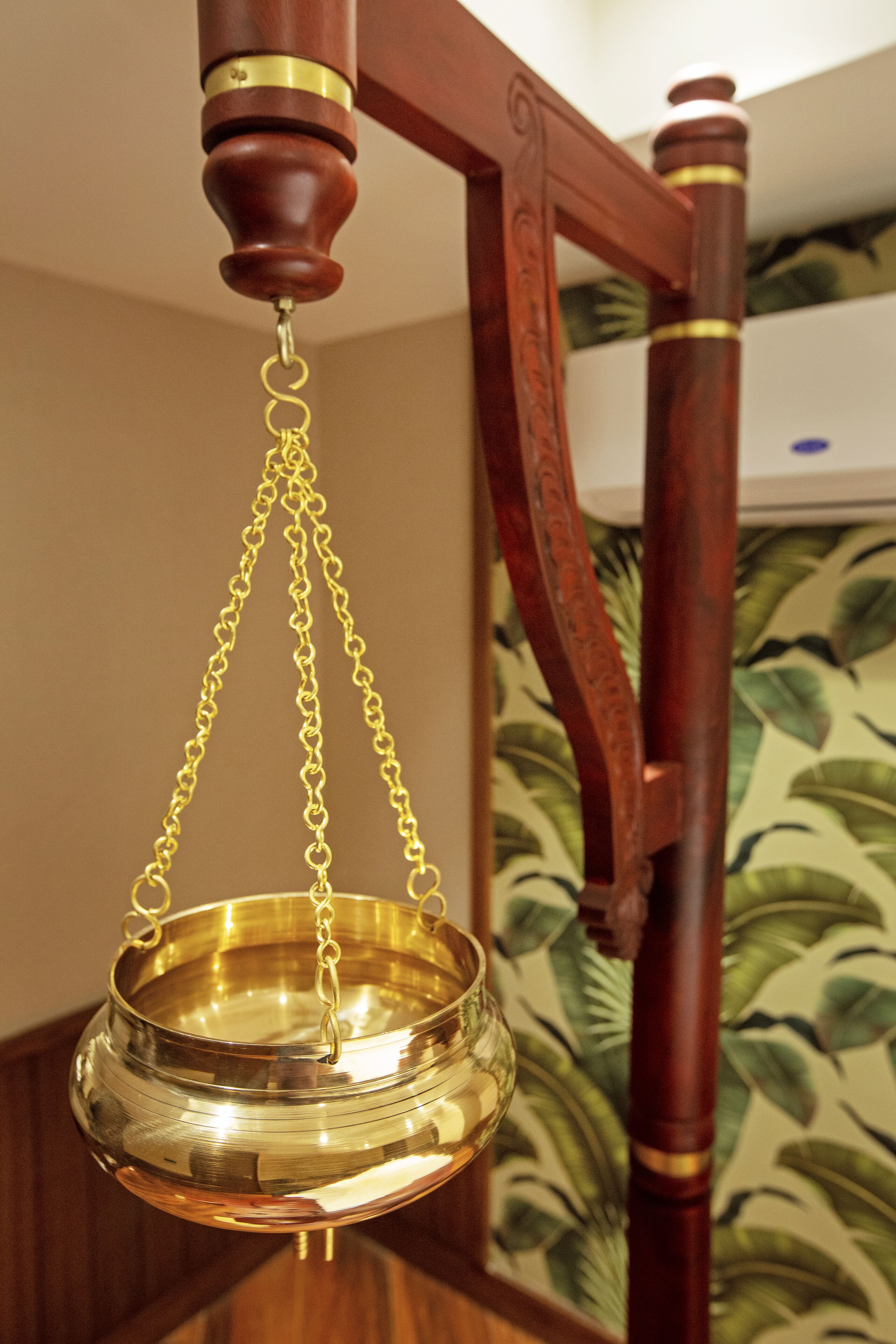 A brass bowl suspended from a wooden stand with a chain.