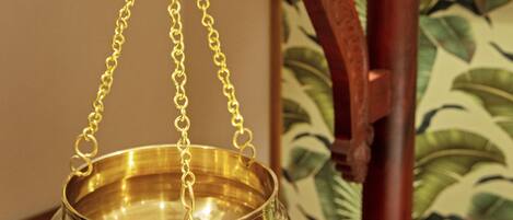 A brass bowl suspended from a wooden stand with a chain.