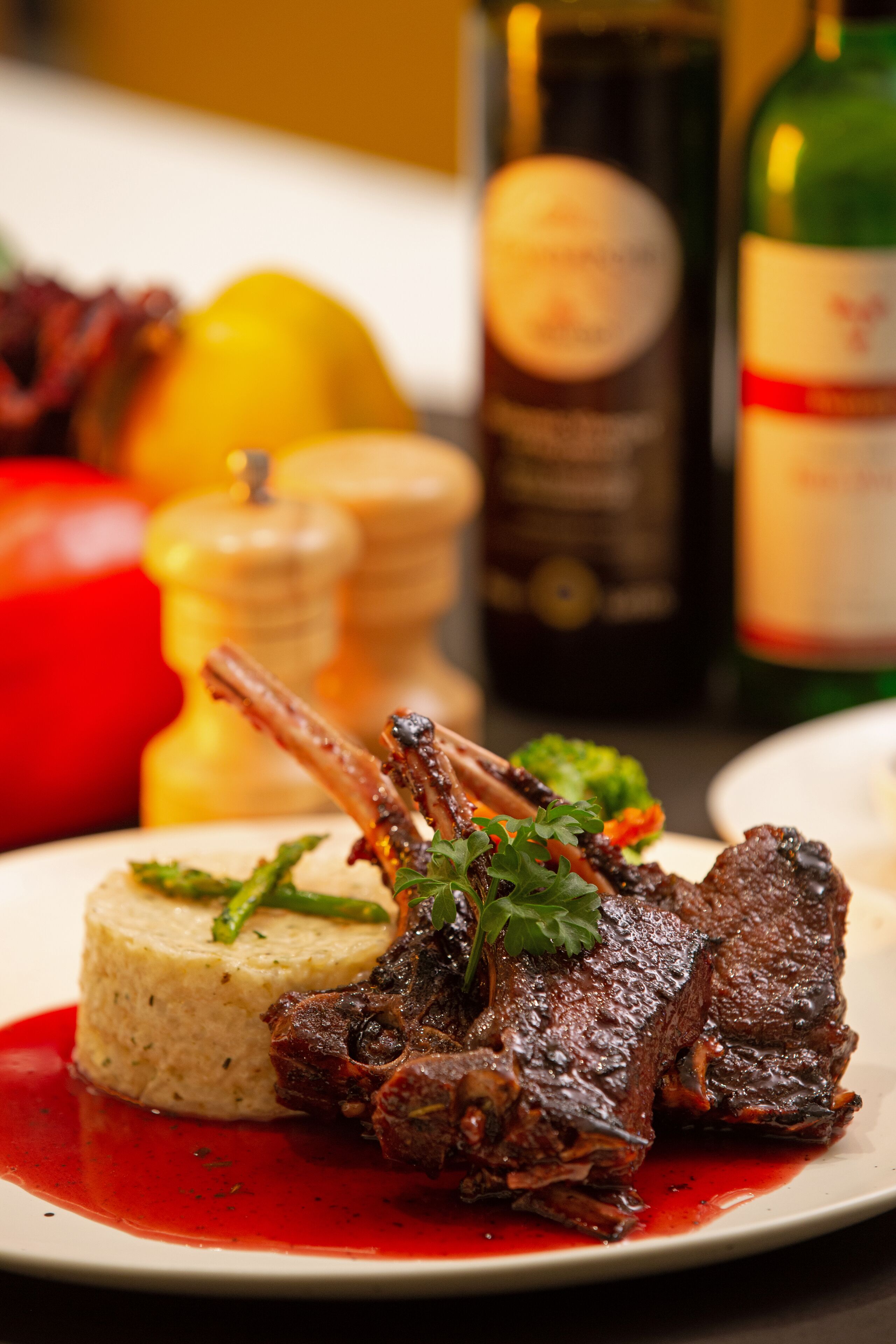 A plate of braised beef short ribs with a red sauce, garnished with parsley, served with a side of mashed potatoes.