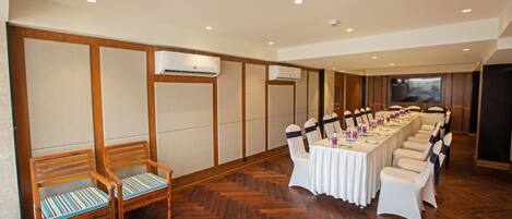 A conference room with a long table, white chairs, and wooden benches.
