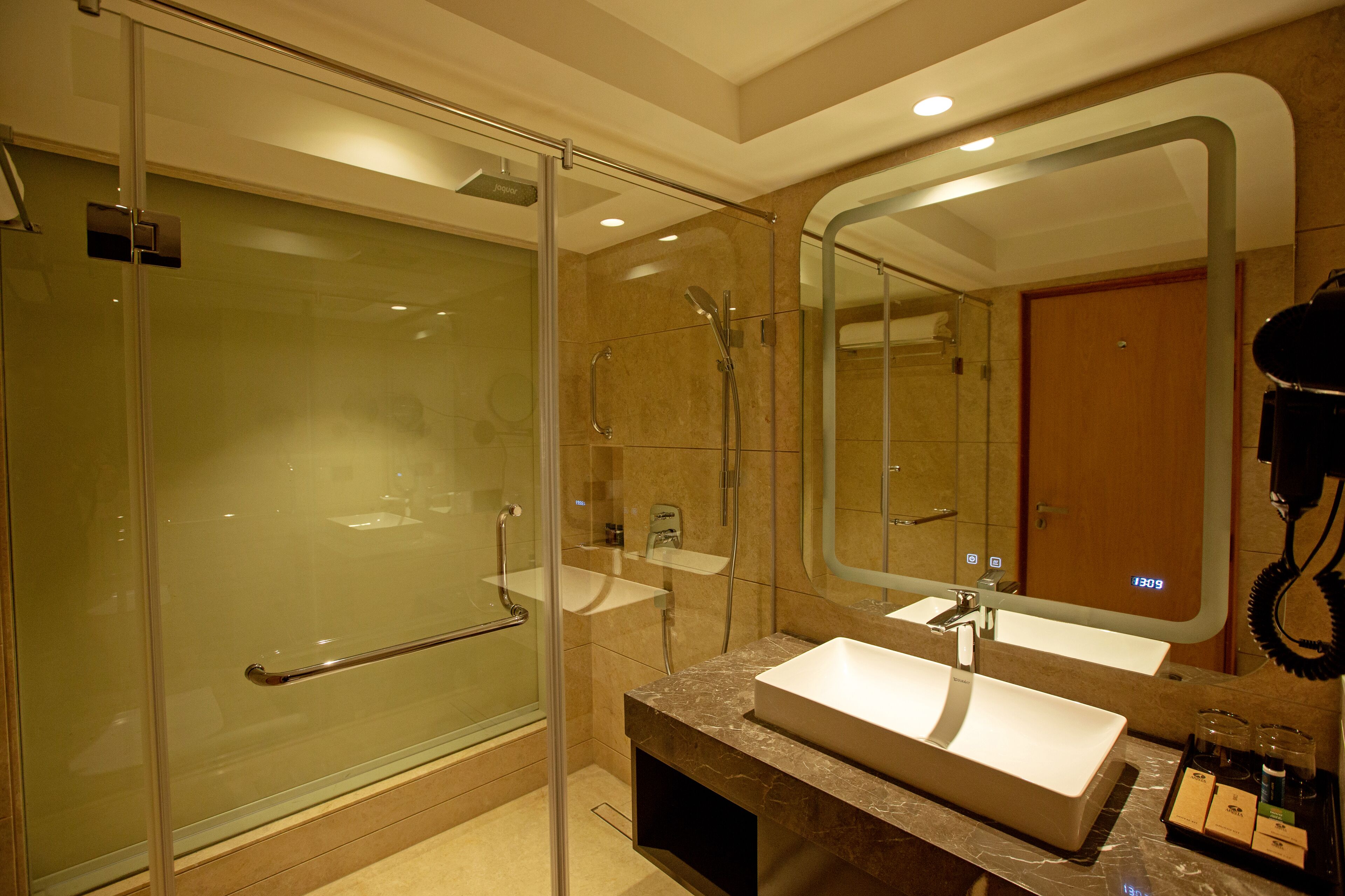 Une salle de bain moderne dotée d’une douche à parois de verre, de deux lavabos et d’un grand miroir.