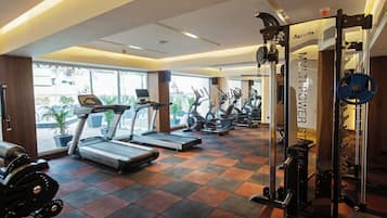 Un gimnasio con cintas de correr, bicicletas estáticas y máquinas de pesas.