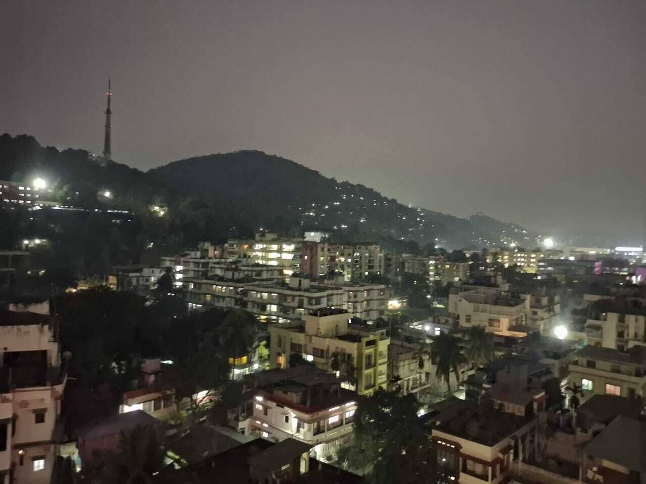 A nighttime cityscape with buildings and a prominent tower.
