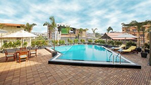 A rooftop pool with a wooden deck, lounge chairs, and a table. - ARISTA BY AMBITION (Guwahati)