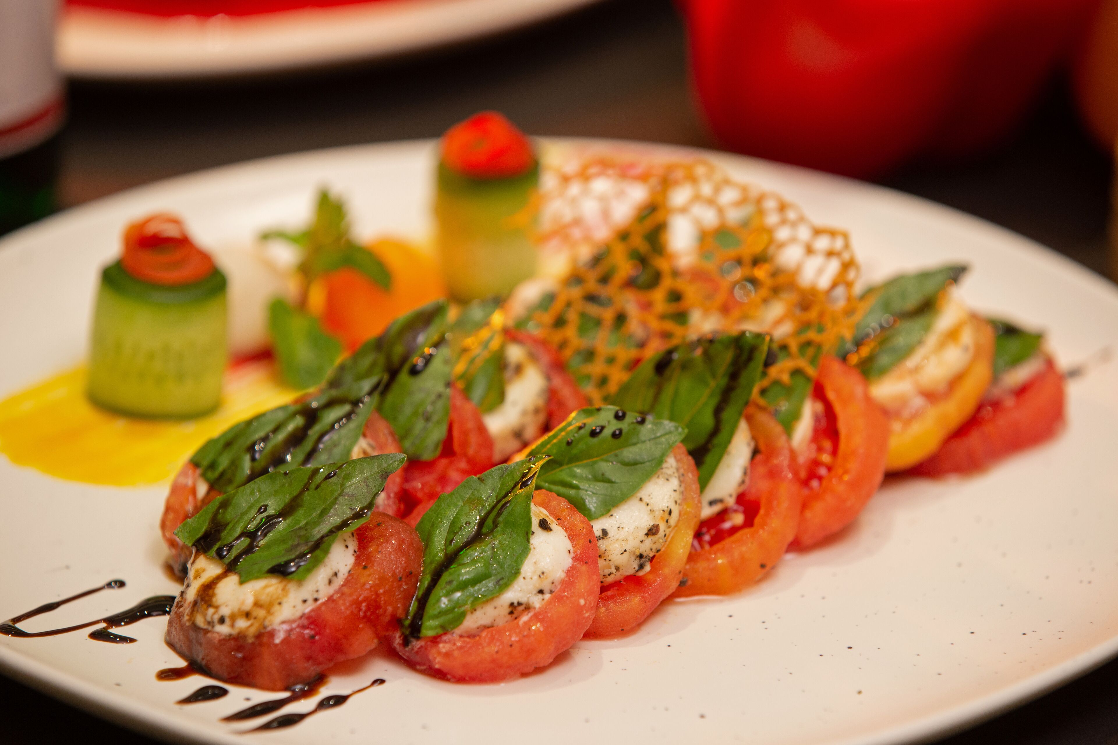 Un plato de aperitivos que incluye tomates rellenos y un vegetal verde decorativo.