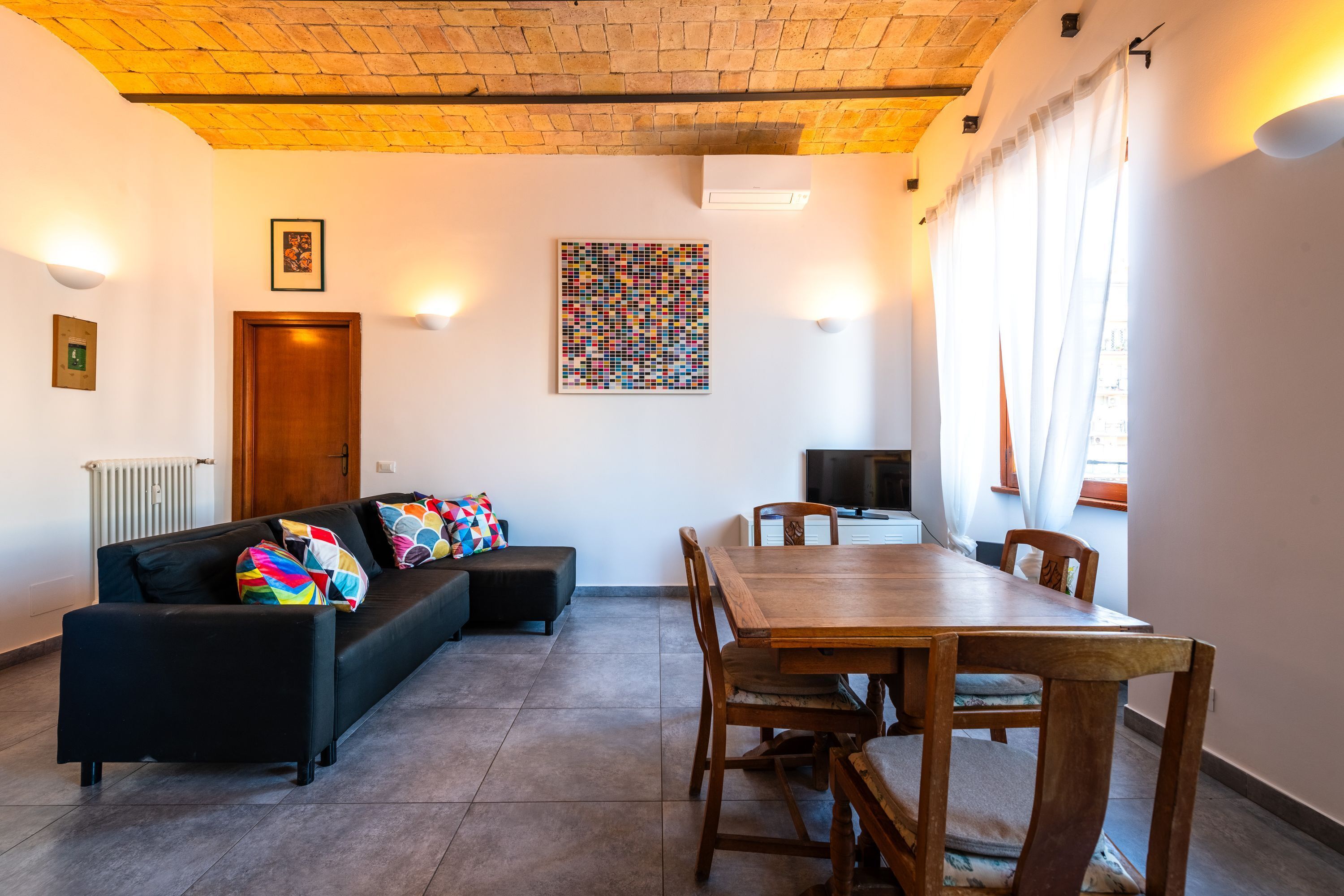 Una sala de estar con un sofá, una mesa de comedor y un televisor.