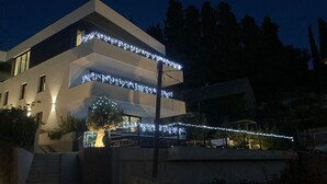 Ein modernes, zweistöckiges Gebäude mit einem Balkon, der mit Lichterketten geschmückt ist.