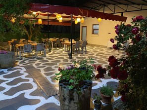 Une terrasse extérieure avec des tables et des chaises, un sol à motifs et des plantes en pot.