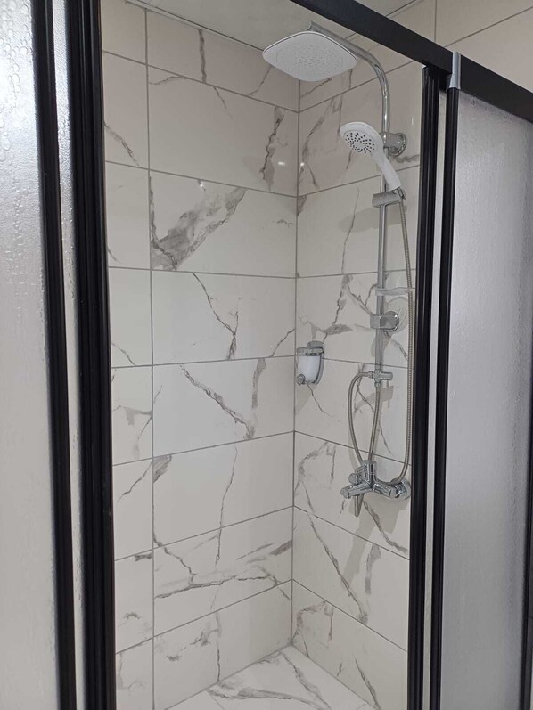 A shower with a handheld showerhead and a wall-mounted faucet. - Olive House (Denizli)