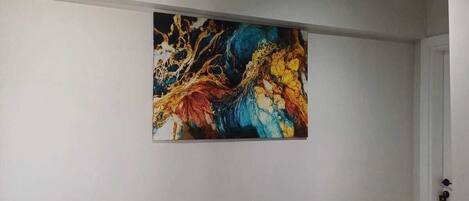 Un pasillo con suelo de mármol y un cuadro abstracto de gran tamaño en la pared.