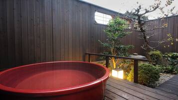 A wooden deck with a hot tub, a small tree, and a wooden fence.