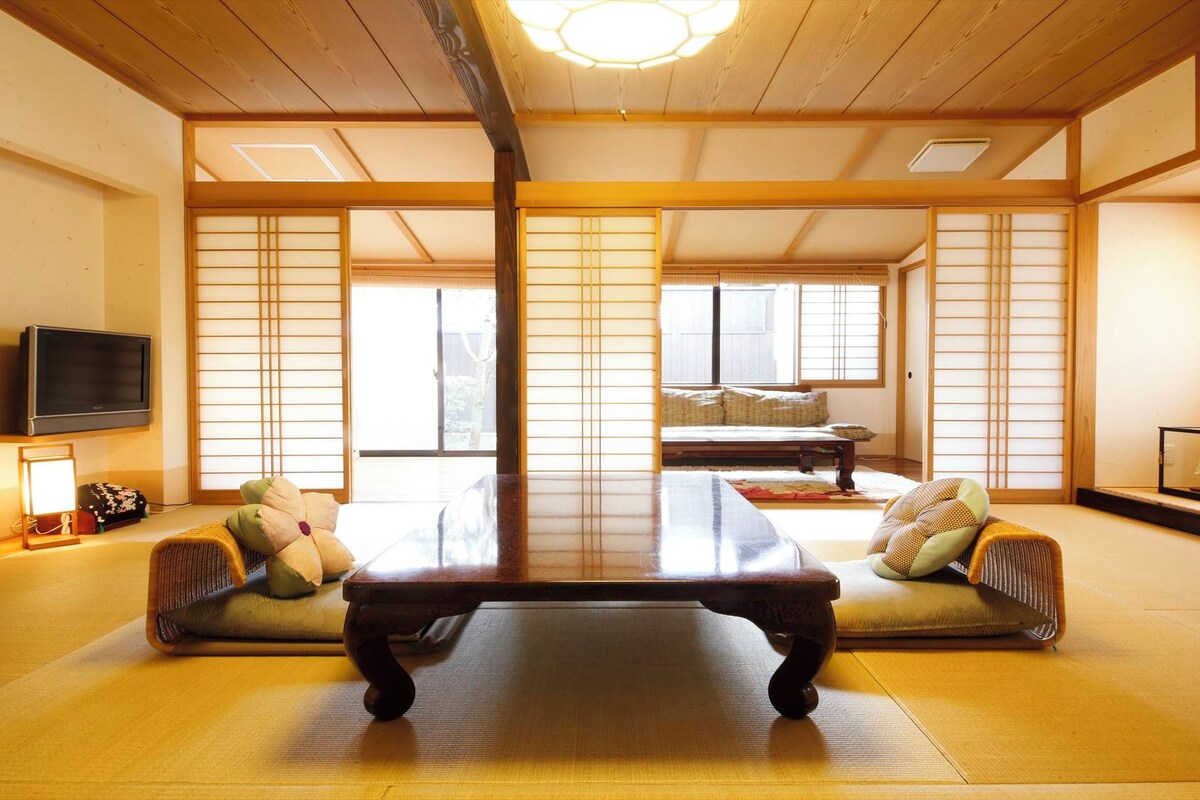 A traditional Japanese room with tatami flooring, a low table, cushions, and sliding doors.