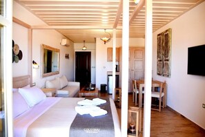 Habitació d'hotel amb llit, sofà, taula de dinar i zona de cuina.