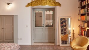 A room with a large wardrobe, a door with glass panels, a bookshelf, and a chair. - Casa Paola in Syracuse (Syracuse)