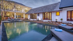 Ein zweistöckiges Haus mit Swimmingpool, Sitzgelegenheiten im Freien und einem gepflegten Garten.