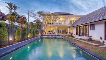 A modern house with a swimming pool, a covered patio, and a well-maintained garden.