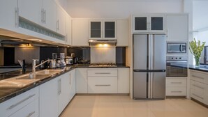 Et moderne køkken med rustfrislåede hårde hvide elementer og en sort bordplade.