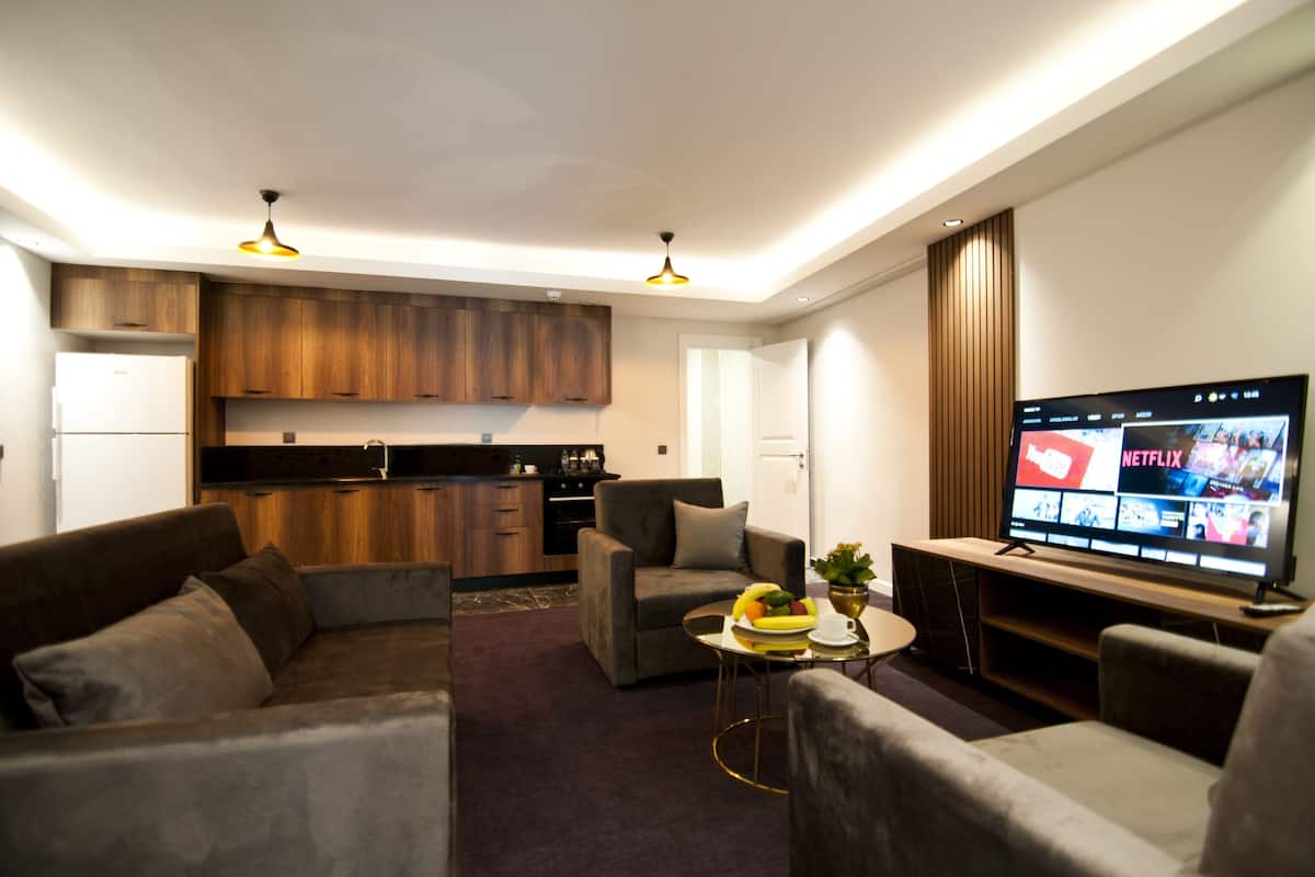 A modern living room with a sofa, a coffee table with fruit, and a flat-screen TV displaying Netflix.