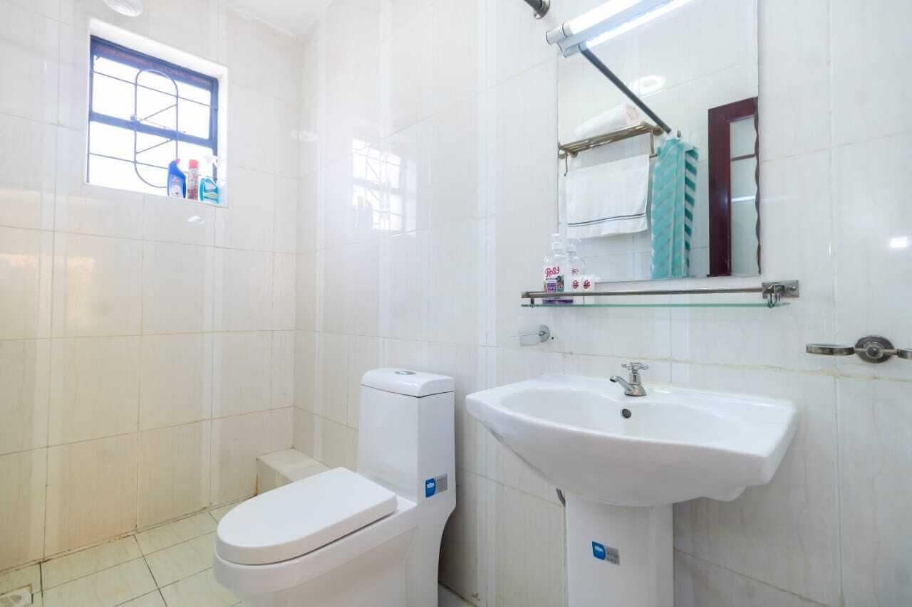 Ein Badezimmer mit Toilette, Waschbecken, Spiegel und Fenster.