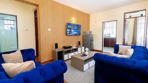 Ein modernes Wohnzimmer mit Fernseher, Sofa und einer Wand aus Holz.