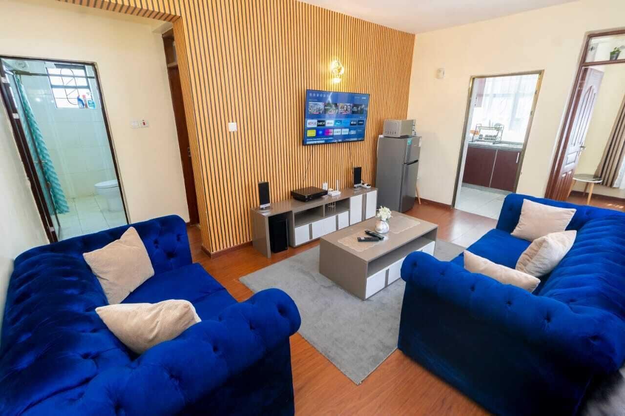 Un salon moderne avec deux canapés bleus, une table basse et un téléviseur à écran plat fixé à un mur en bois.