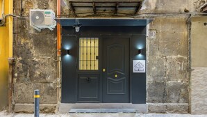 A black door with a barred window, a security camera, and a small sign indicating a room with a view. - Casa Fernanda (Naples)