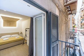A modern hotel room with a bed, a balcony, and a view of the street. - Casa Fernanda (Naples)