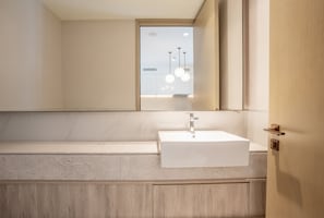 A modern bathroom with a white sink, a large mirror, and a wooden vanity. - Zapbed House - ADP 1909 (Dubai)