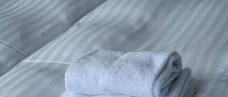 A hotel room with two beds, white bedding, and a folded towel on the bed.