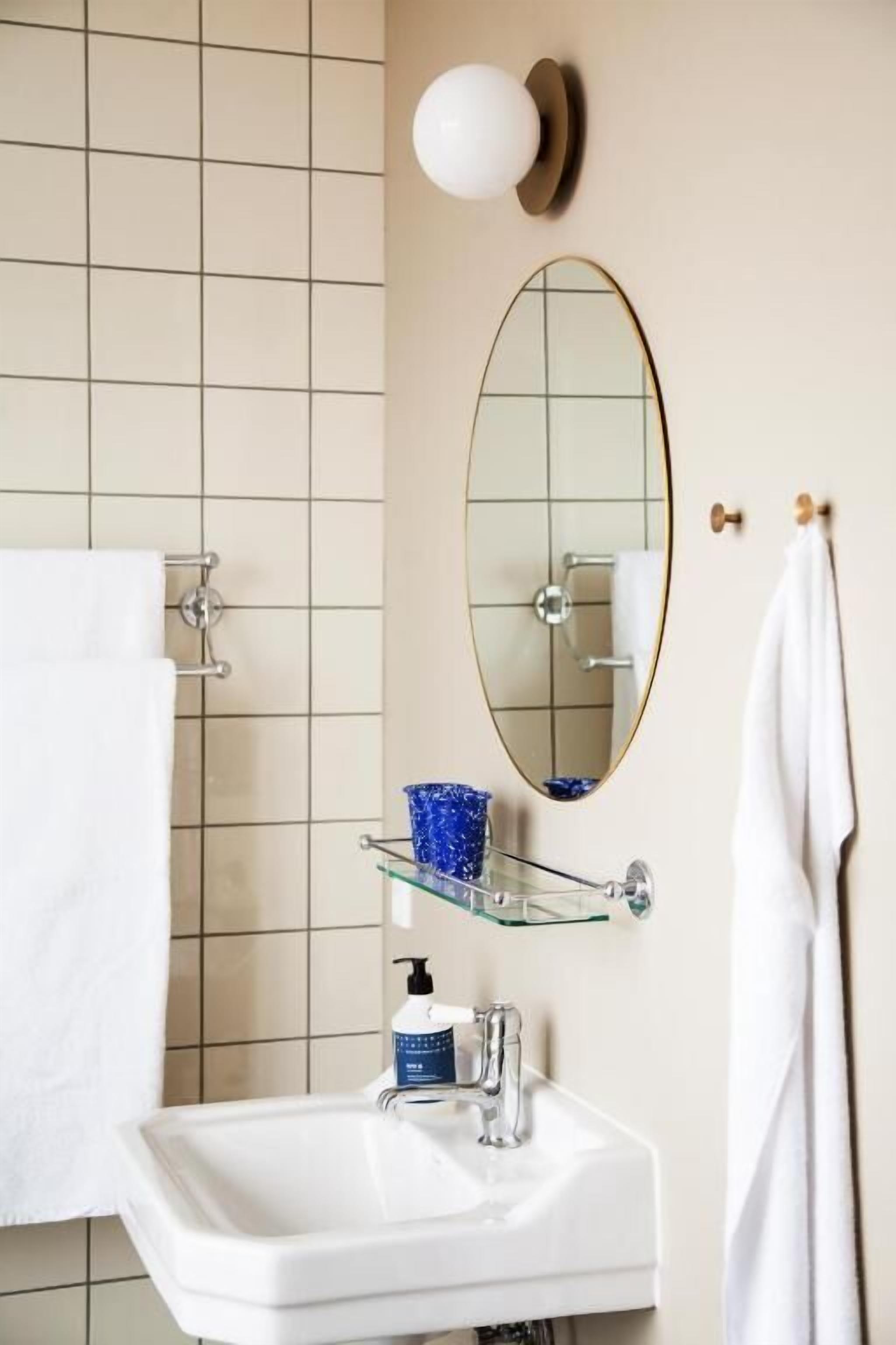 A bathroom with a white sink, a mirror, and a towel rack.