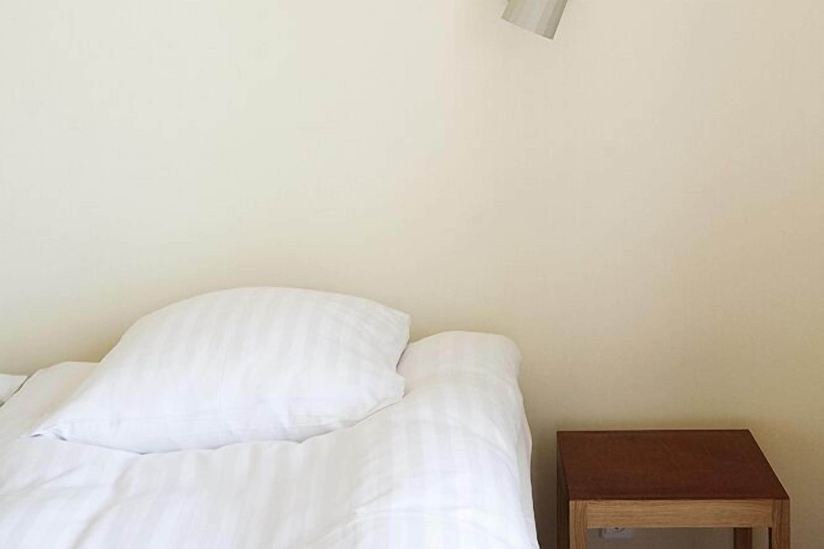 Een eenvoudige kamer met een bed en een klein houten nachtkastje.