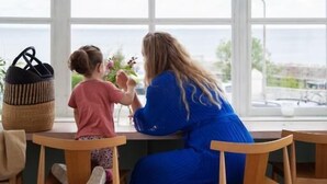 Dos personas sentadas a una mesa junto a un ventanal con vistas al exterior.