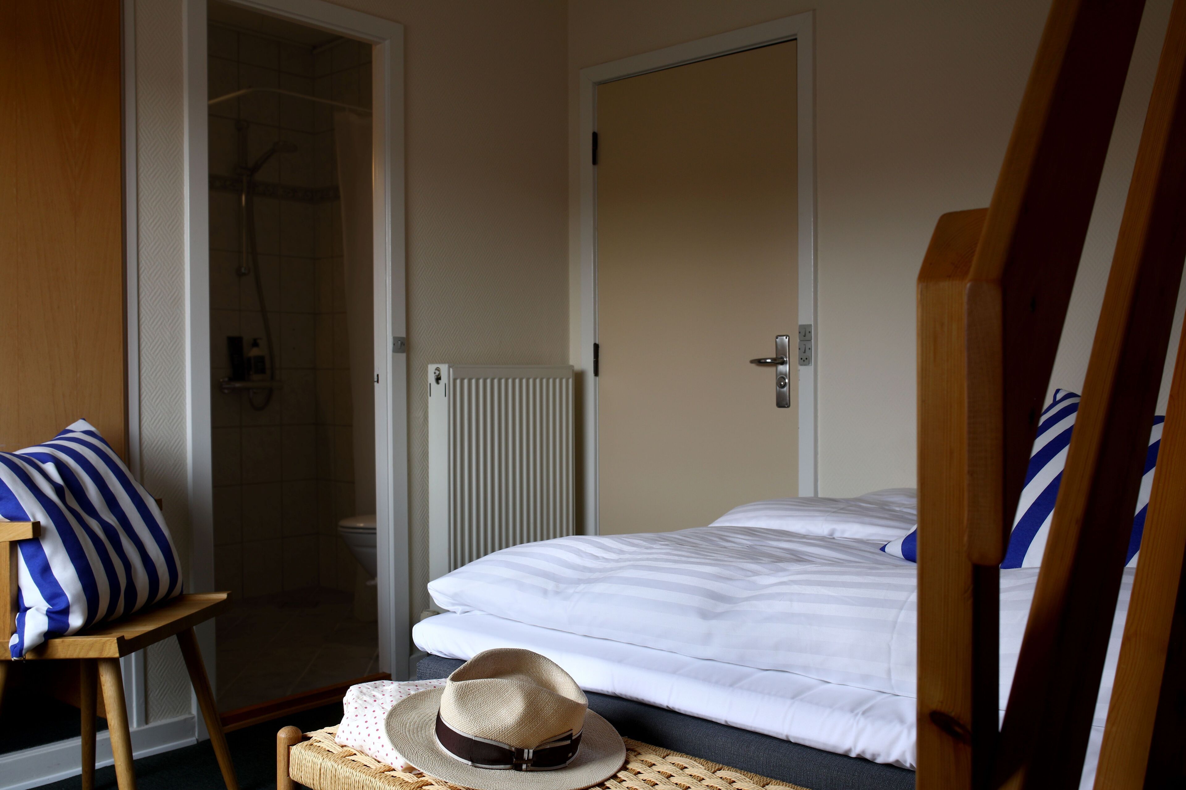 A hotel room with a bed, a shower, and a wooden chair.