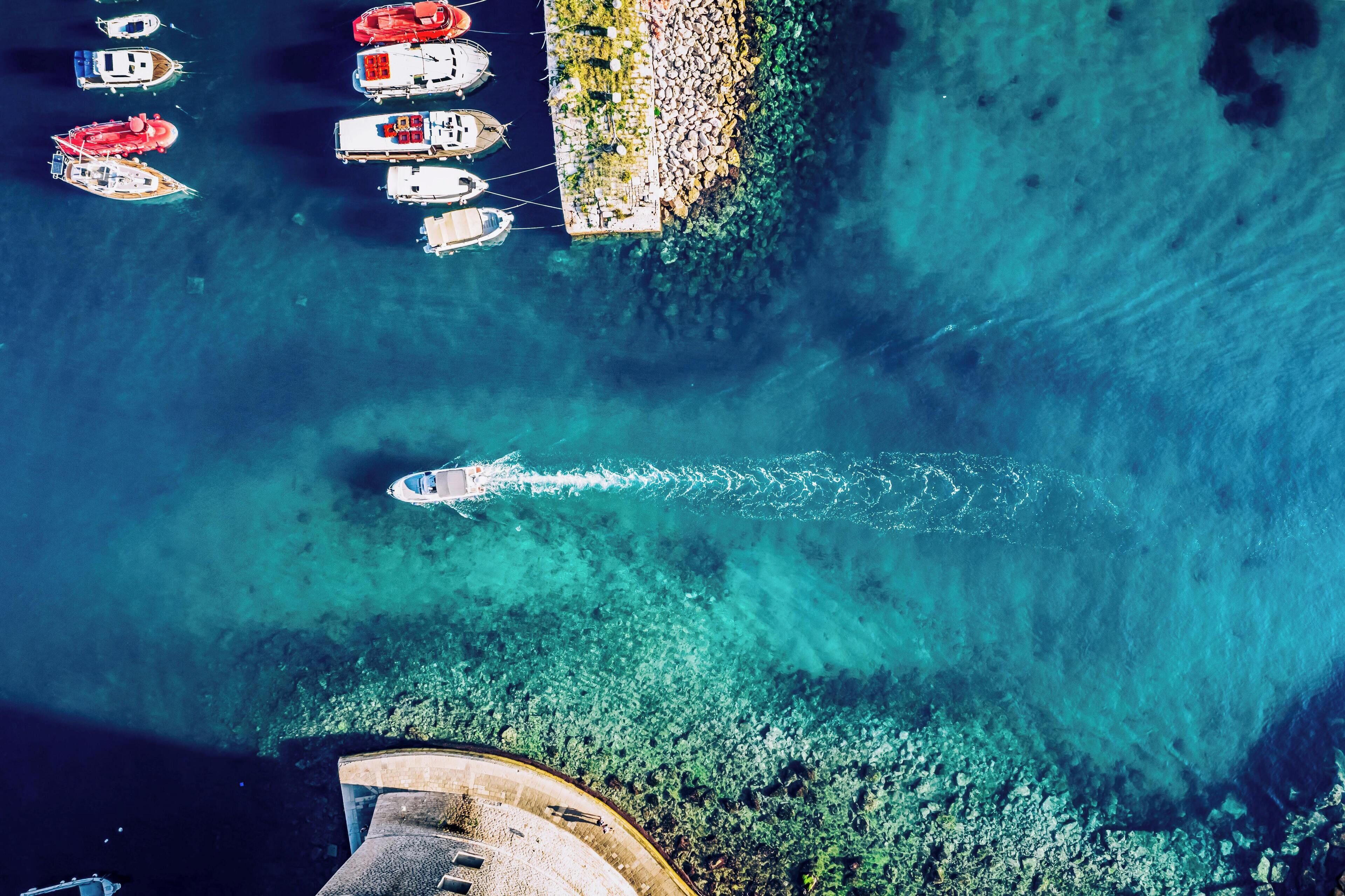 An aerial view of a marina with several boats docked and a clear blue sea.