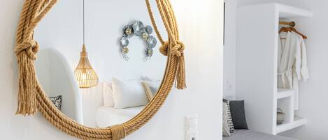 A modern bathroom with a round mirror, a hanging light fixture, a small potted plant, and a book on the vanity.