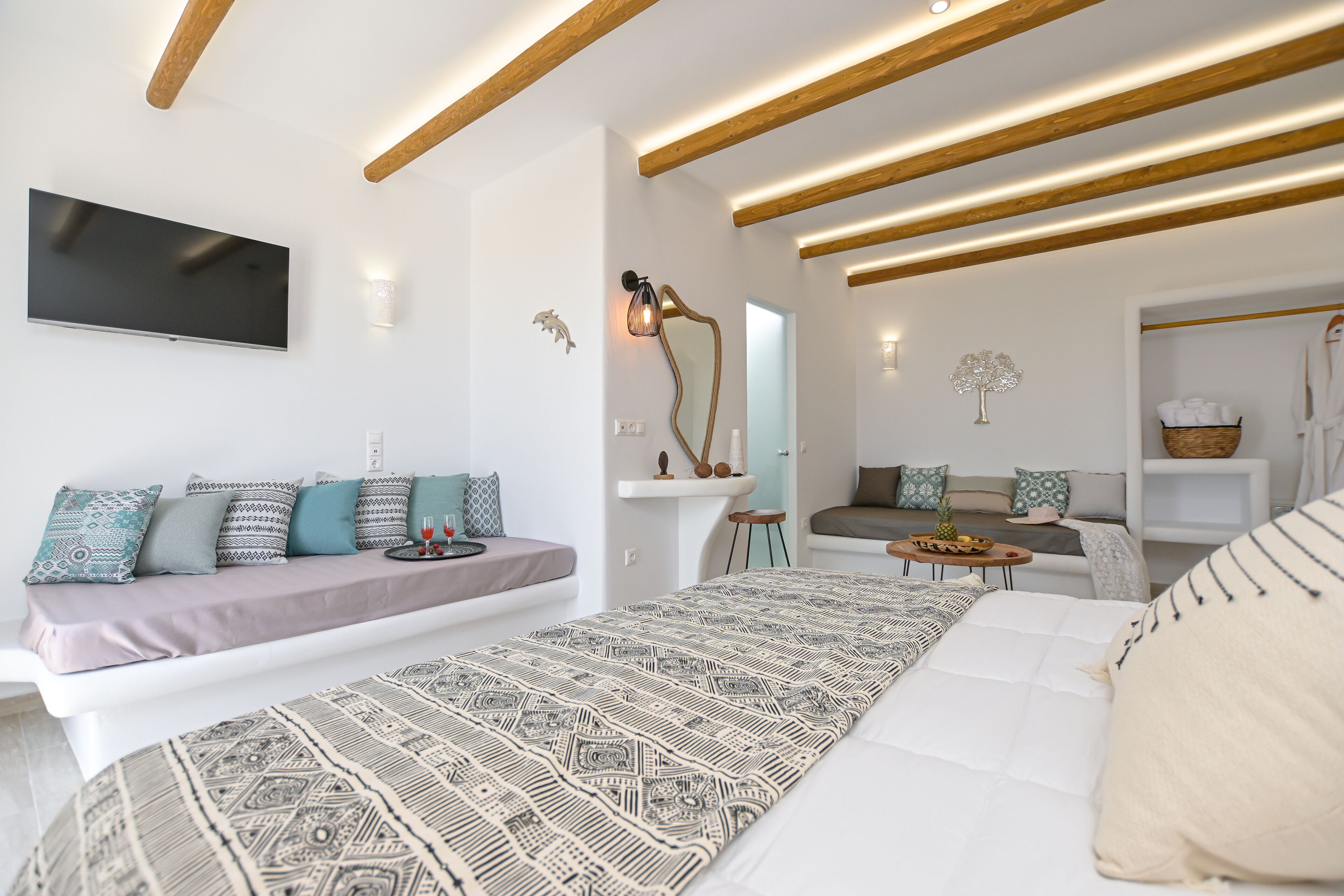 Un dormitorio moderno con una cama grande, un sofá, un televisor y una zona de comedor.