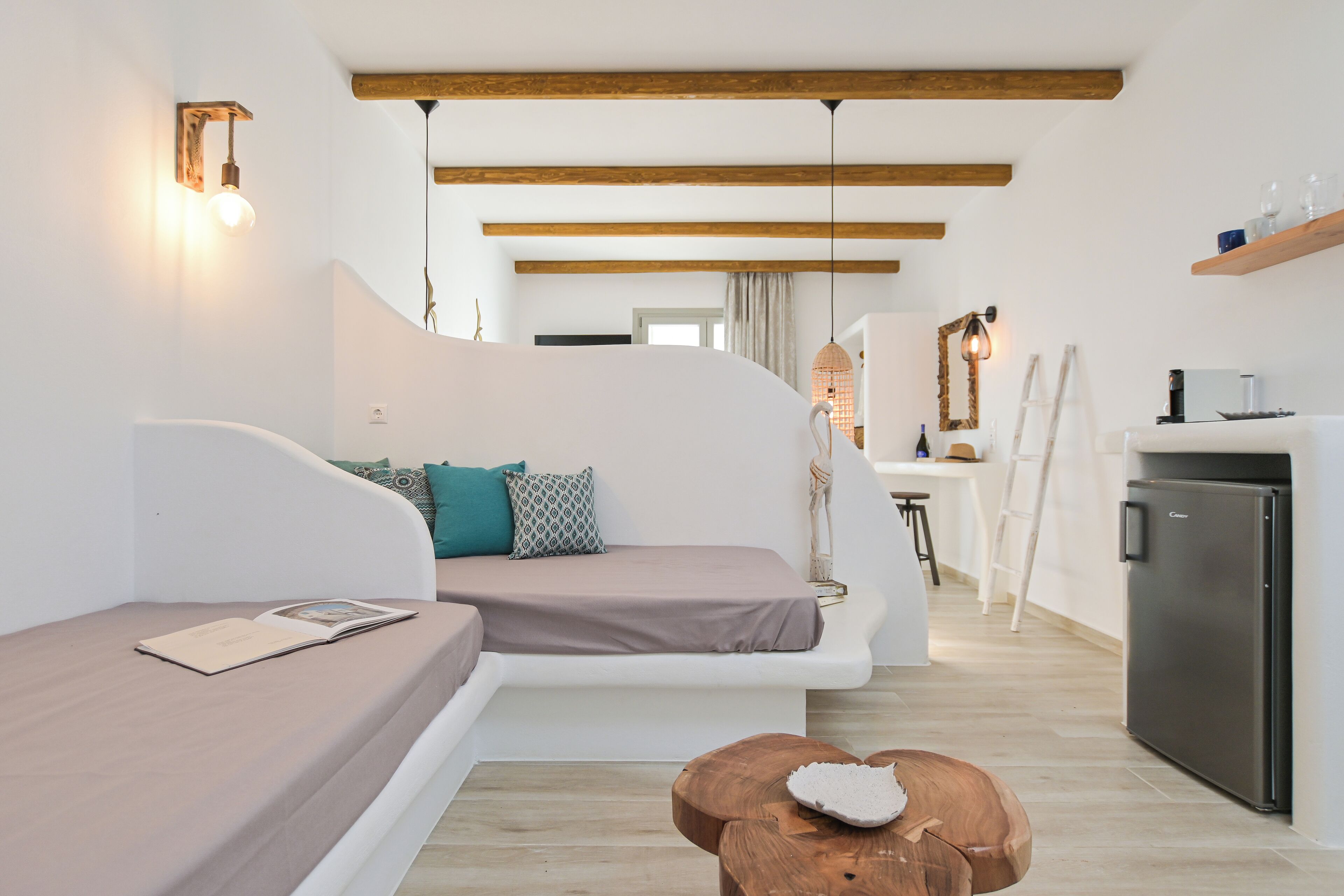 Ein modernes Wohnzimmer mit einer Couch, einem Holztisch und einer Küchenzeile mit einem Kühlschrank.
