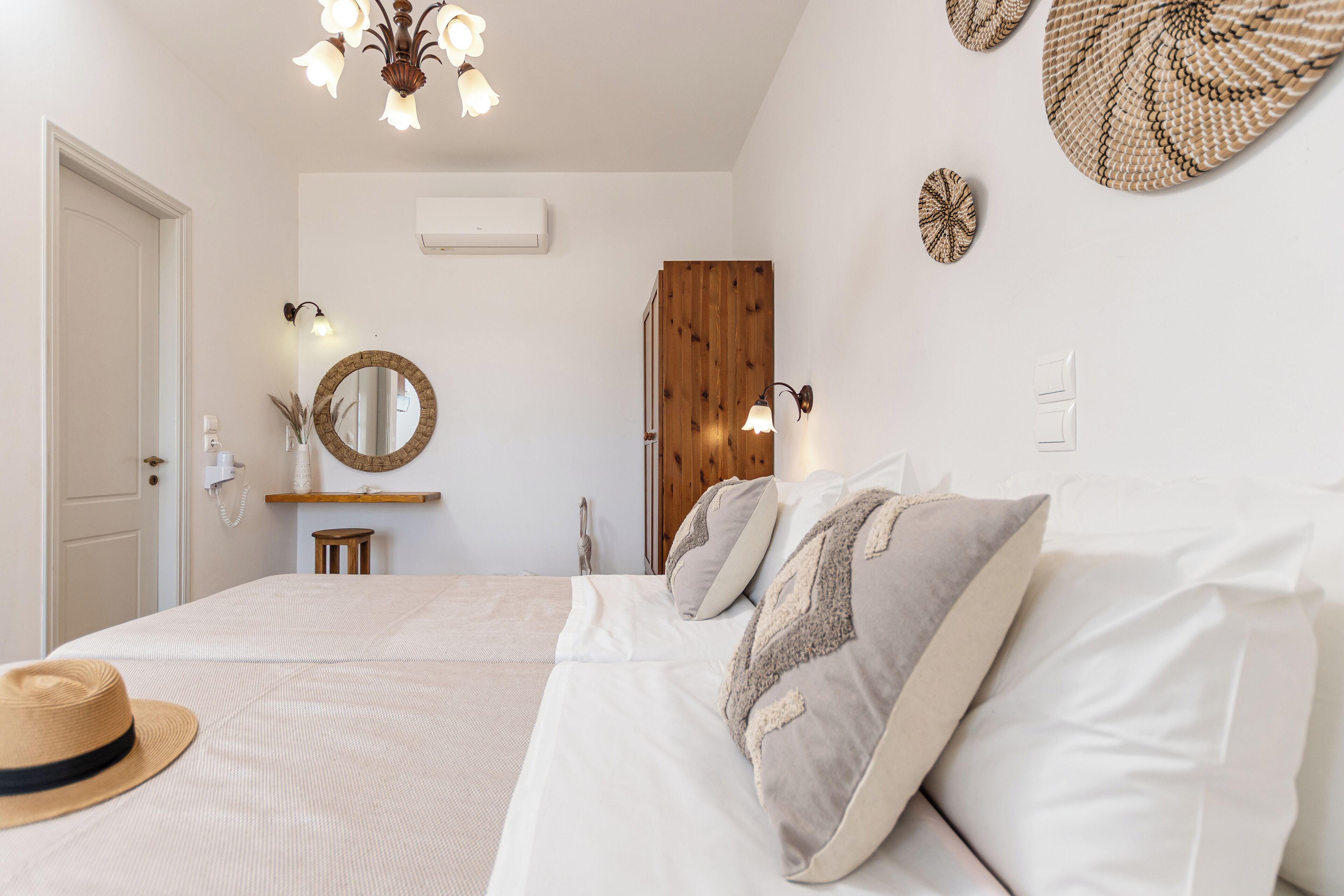 A bedroom with a bed, a hat, a mirror, wall-mounted lights, and a wooden door.