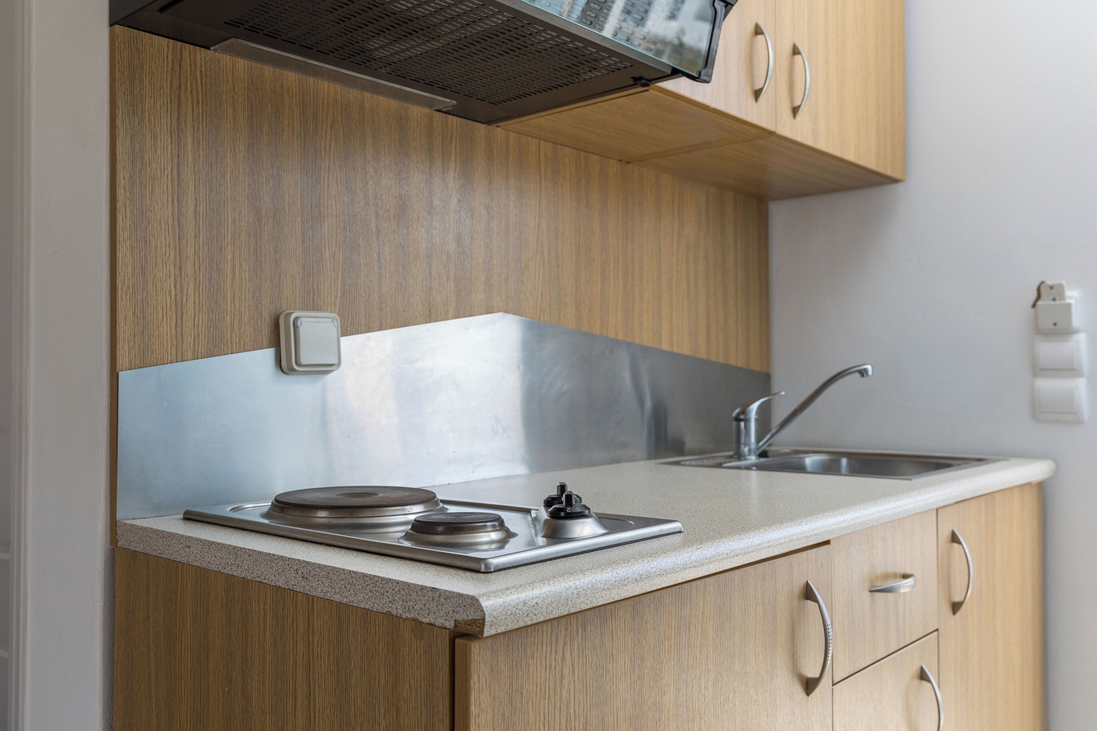 A modern kitchen with wooden cabinets, a stainless steel sink, and a built-in microwave.