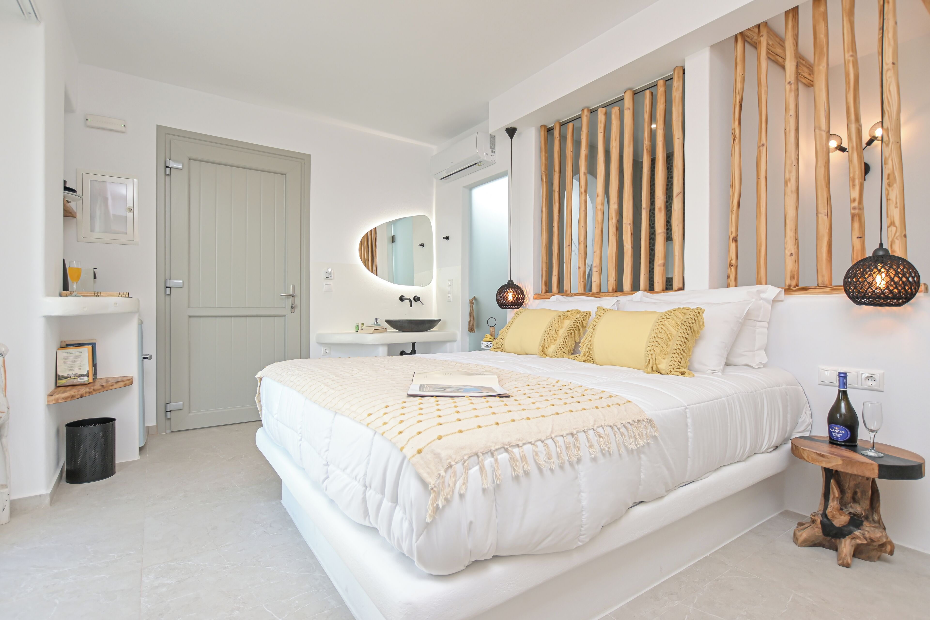 A bedroom with a large bed, bedside table, and a mirror.