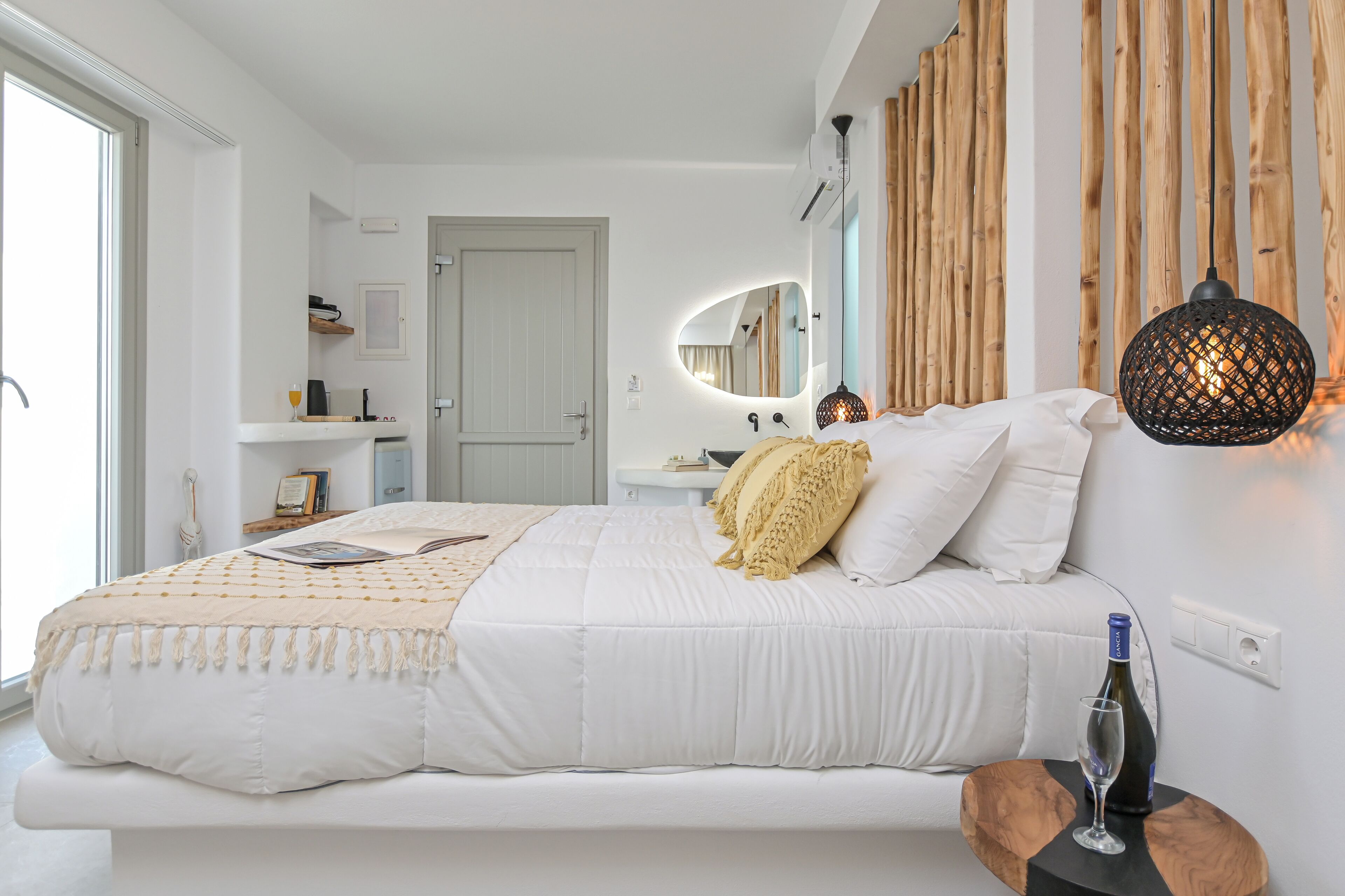 A modern bedroom with a large bed, bedside tables, a mirror, and a hanging light fixture.