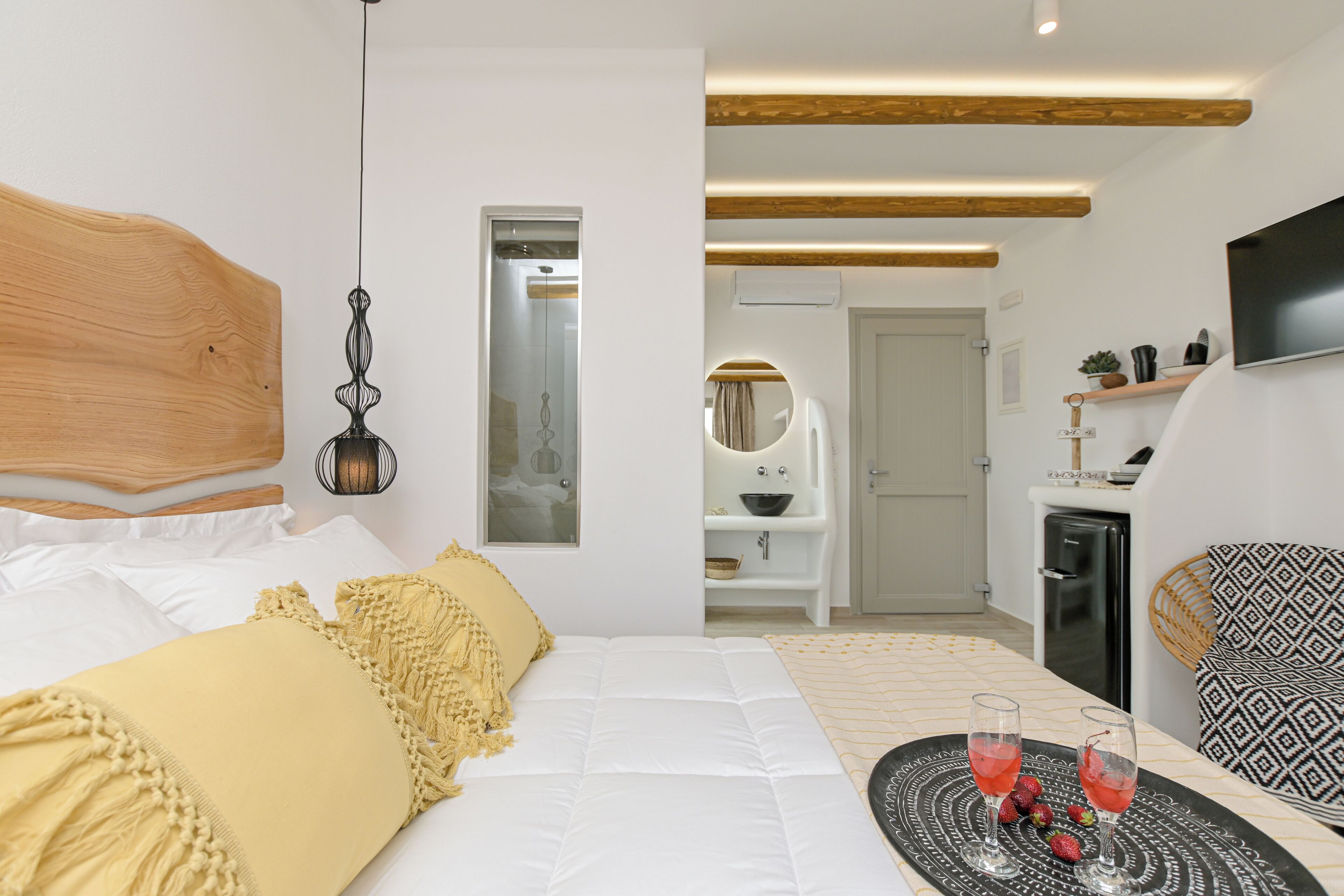 A modern hotel room with a bed, bedside table, and a small seating area with a TV.